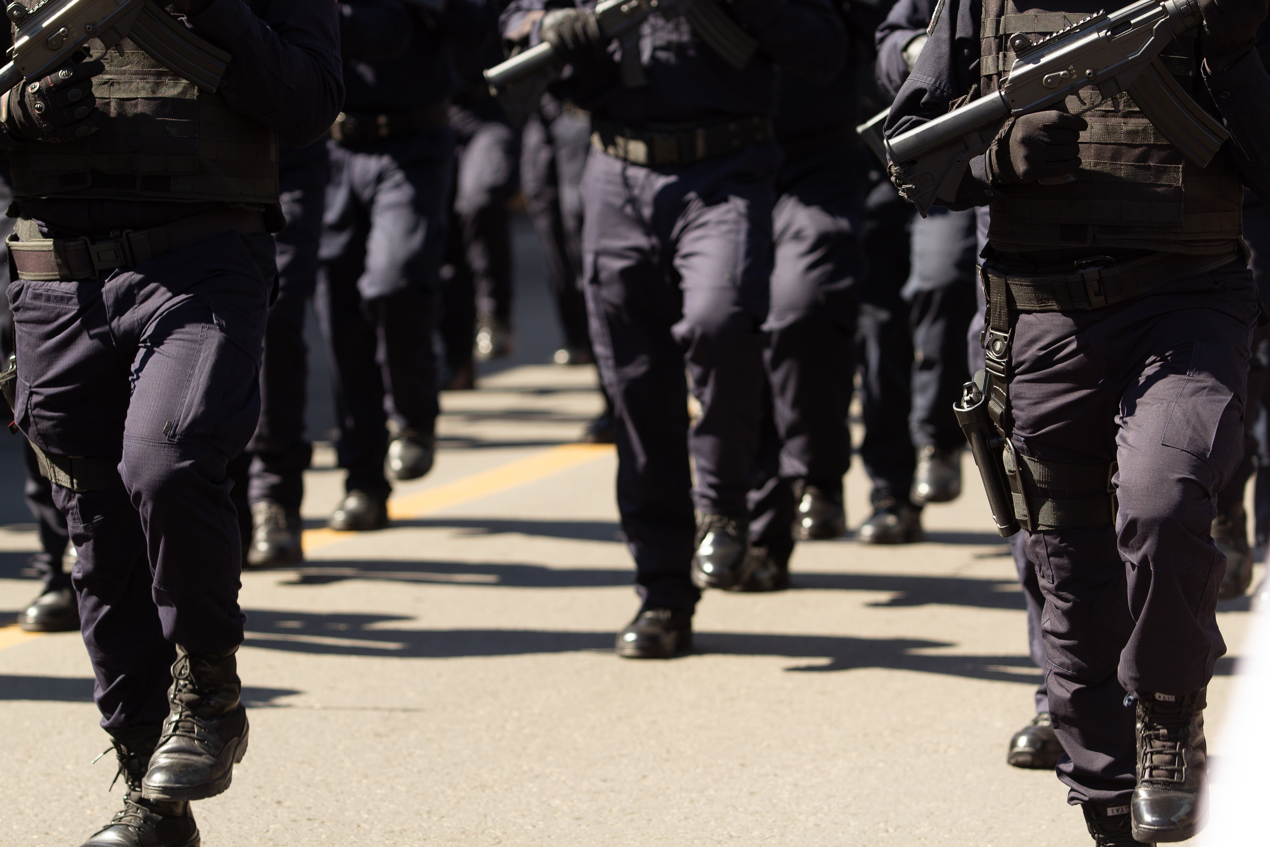 Leg short of police walking in sync in dark uniforms