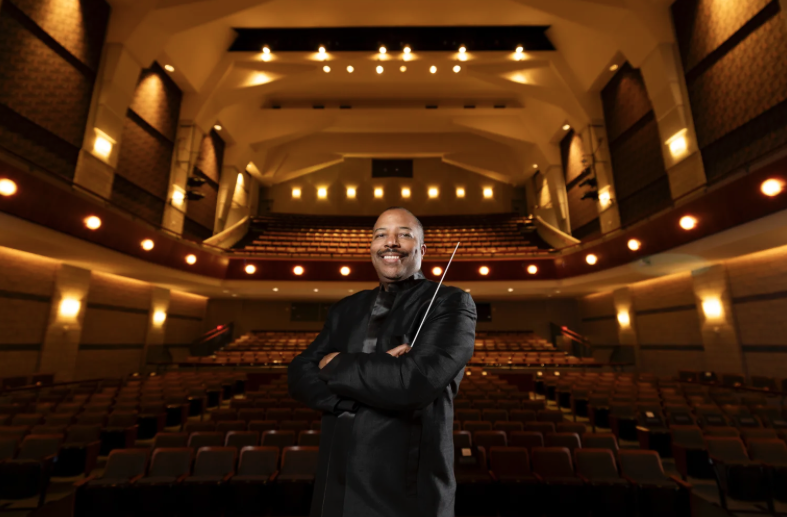 photo of man in performance hall, seats and lights in background