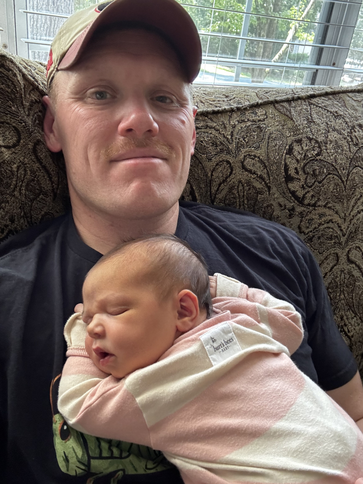 Alex with his baby daughter on his chest 