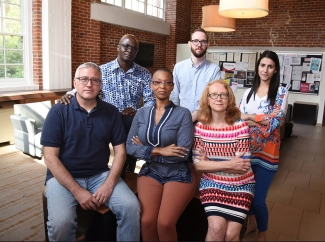 photo of six people, inside with brick wall