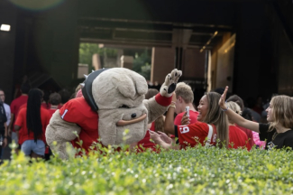 photo of student high-fiving mascot in Dog costume