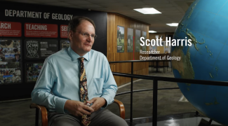 video still photo of man, globe and wall in background