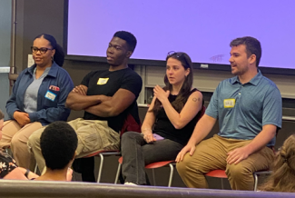 photo of four people seated with name tags, audience