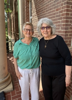 photo of two people, building in background, day