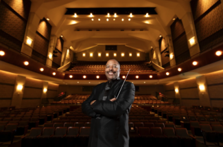 photo of man in performance hall, seats and lights in background