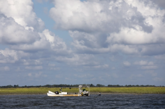 photo of sea, clouds, sky and marsh, with boat day