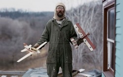 man with model airplanes on porch.