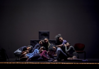 photo of people sitting close together on a darkened stage