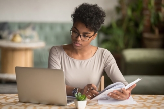 photo of woman with book and laptop