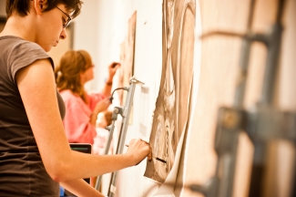 photo of people drawing on paper attached to a wall