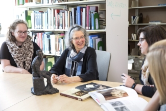 photo of four women sitting at a table with a small sculpture