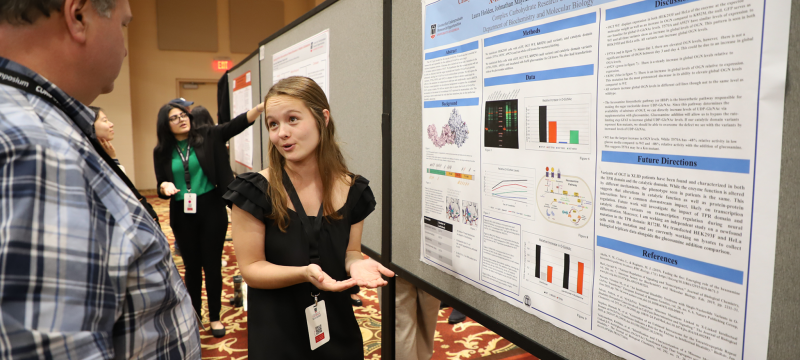 photo of people speaking in front of posters, ballroom