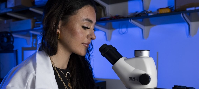 photo ofo woman with microscope, lab coat, gloves