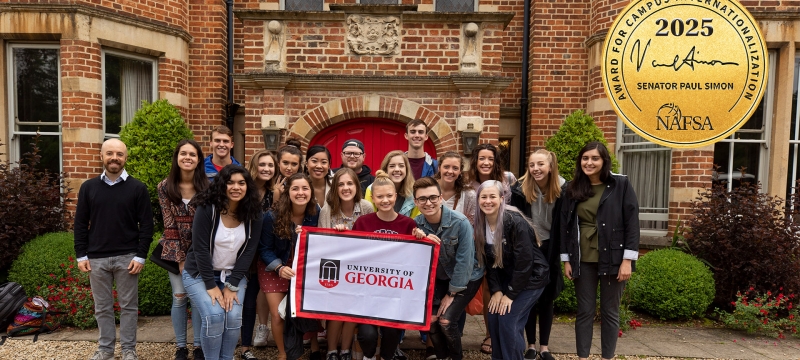 group photo of people in front of old brick building, holding flag