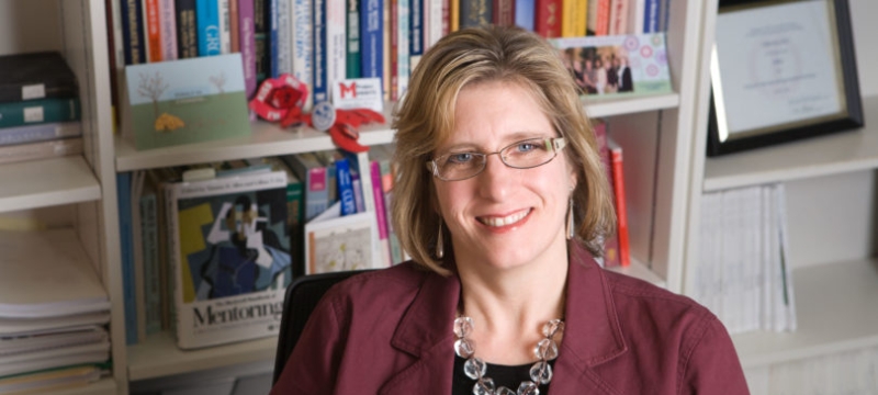 photo of woman sitting in front of bookshelves
