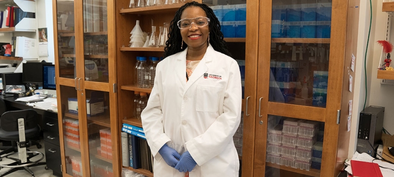 photo of woman in laboratory, in what lab coat with shelves and bottles