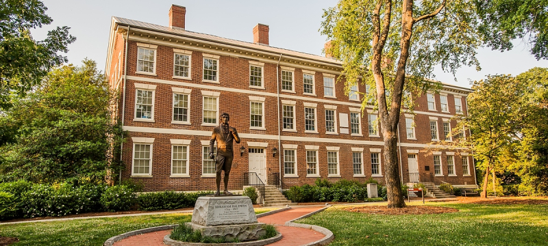 Photo of story building on campus, with statue in front, day.