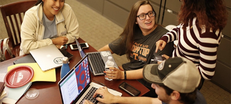 photo of four people at a table, with laptop
