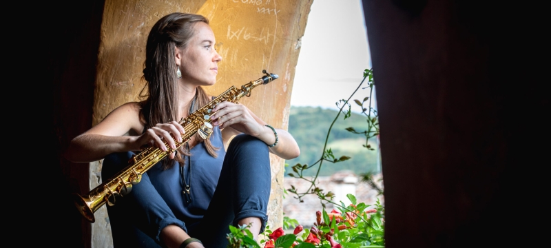 photo of woman sitting in arch opening with musical instrument
