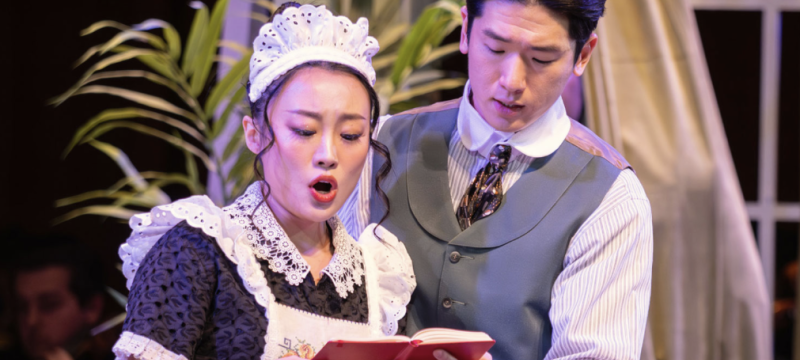 photo of man and woman holding book, woman singing