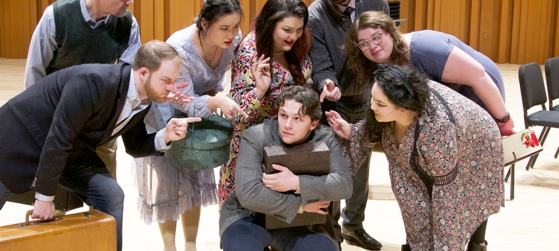 photo of eight people on a stage with suitcases