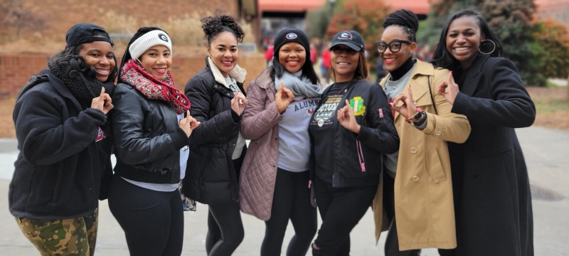photo of seven women outdoors, with stadium in background