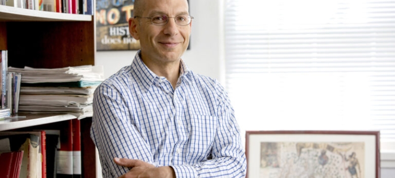 photo of man in office with framed map, books