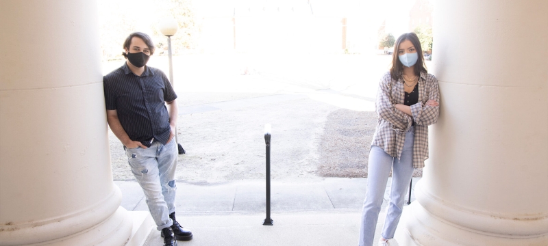 photo of two people leaning against columns, day