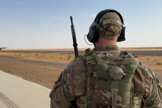 Alex Asay in military uniform standing on road in desert