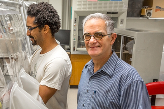 two men in a lab, one looking at camera