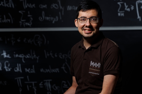 photo of man, chalkboard with letters and numerals in background