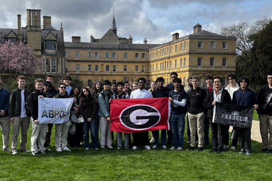 Students holding G banner in front of buildings