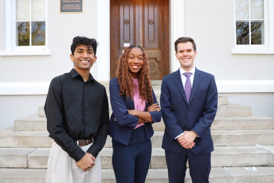 photo of three people, building in background, day