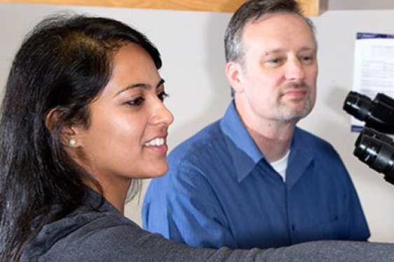 student with professor and microscope